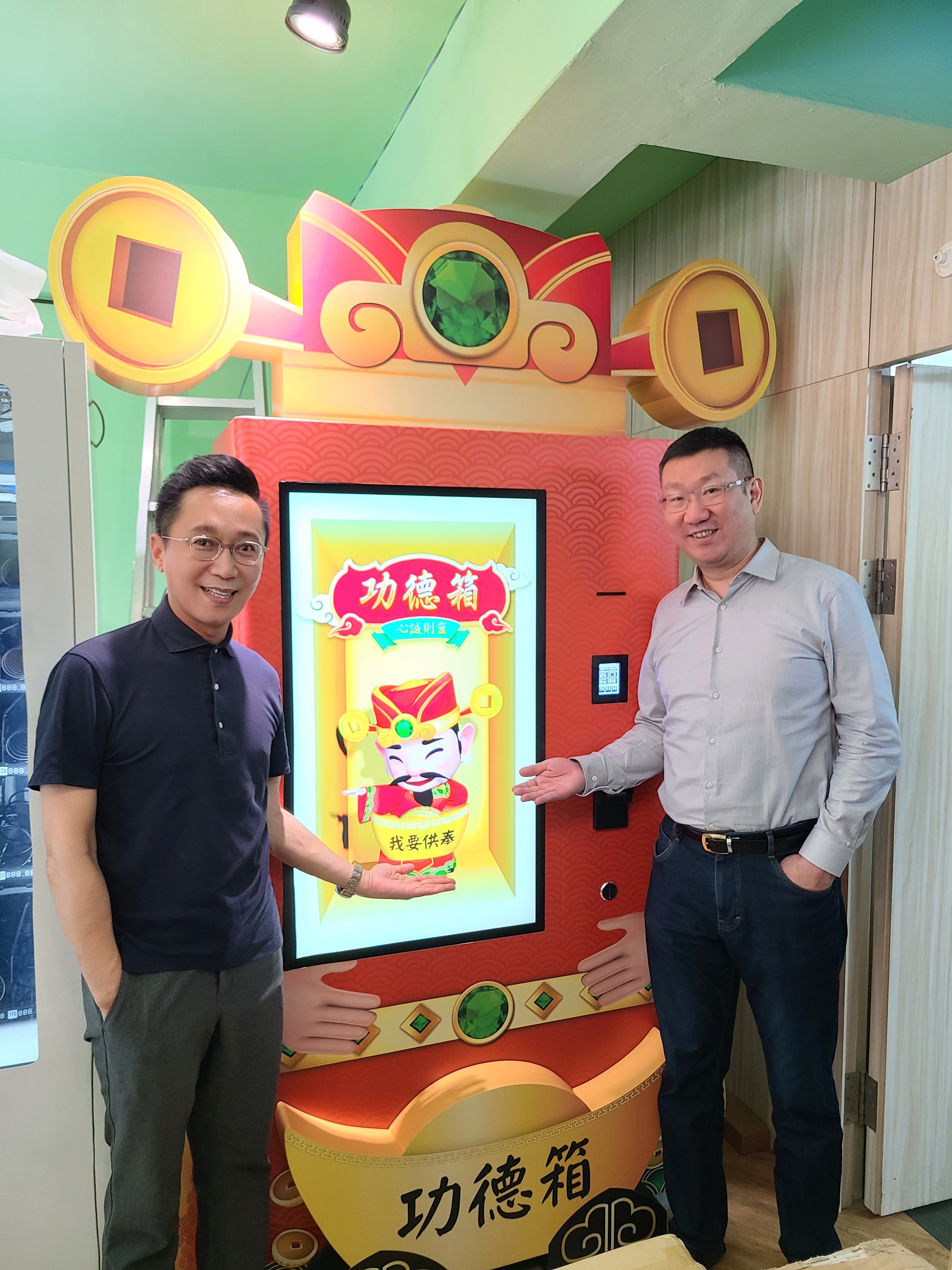 數位功德箱產品實機，觸控螢幕顯示動態神明角色與「我要供奉」按鈕