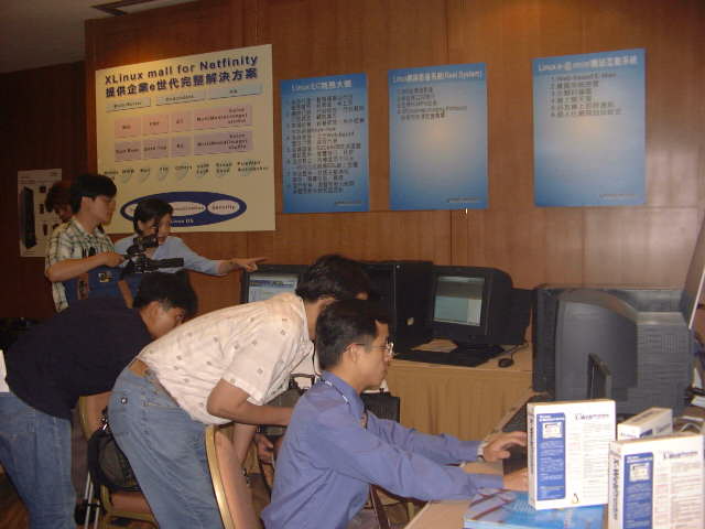 XLinux產品展示區，牆上貼有「XLinux mail for Netfinity」等產品說明海報，多台電腦供現場操作